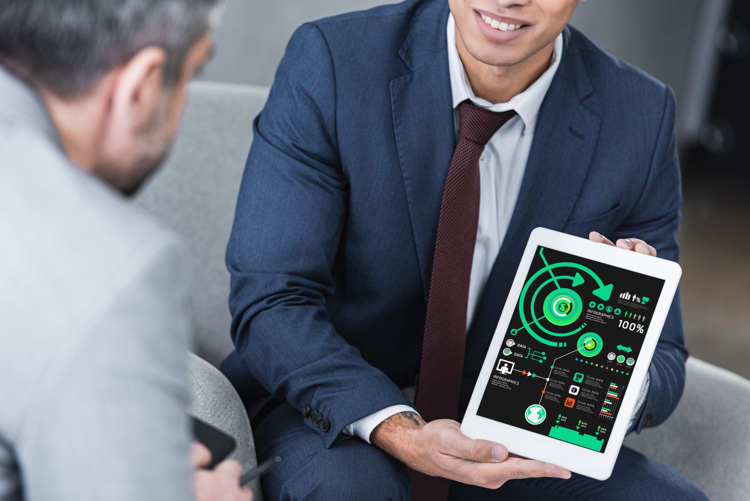 cropped shot of young businessman showing digital tablet with business charts to colleague
